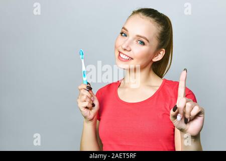 Junge schöne Frau ist bei der Reinigung der Zähne beschäftigt. Schönes Lächeln Gesunde weisse Zähne. Ein Mädchen hält eine Zahnbürste. Das Konzept der Mundhygiene Stockfoto