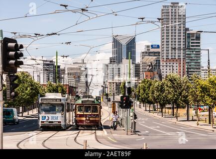 Melbourne, Australien - 16. November 2009: Stadtbild mit hohen Gebäuden und Straßen-Szene mit 2 Straßenbahn an der Haltestelle mit Ampel und Personen unter lig Stockfoto
