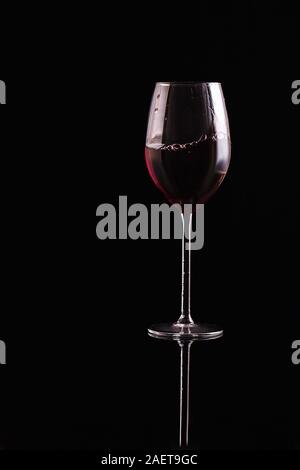 Glas Rotwein auf schwarzem Hintergrund. Aromatischer Wein. Strengen Stil. Wein auf der dunklen Stockfoto
