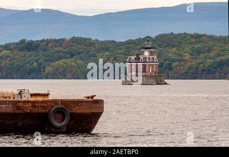 Eine rostige alte Barge sitzt im Vordergrund in der Nähe des Hudson Athen Leuchtturm in Upstate New York USA Stockfoto