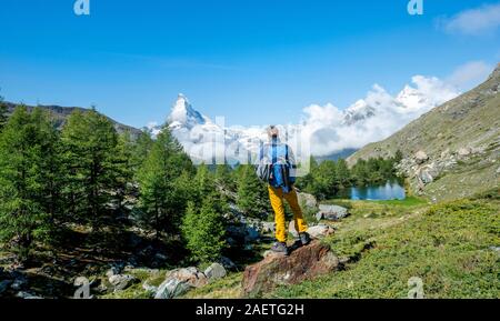 Wanderer steht auf Felsen und in die Ferne schaut, hinter dem See Grindij und Schnee - Matterhorn, Wallis, Schweiz abgedeckt Stockfoto