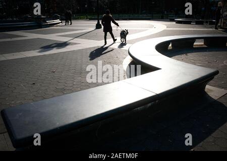 Fußgänger gehen Hund durch Washington Square, NEW YORK CITY, im Winter Licht. Stockfoto