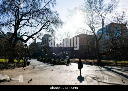 Fußgänger Spaziergang durch Washington Square, NEW YORK CITY, im Winter Licht. Stockfoto