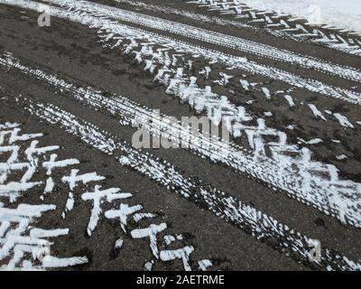 Trace von verschiedenen Reifen auf Asphalt in der Wintersaison Stockfoto