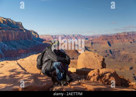 Mann sitzt und bewundern Sie die Aussicht auf den Grand Canyon Stockfoto