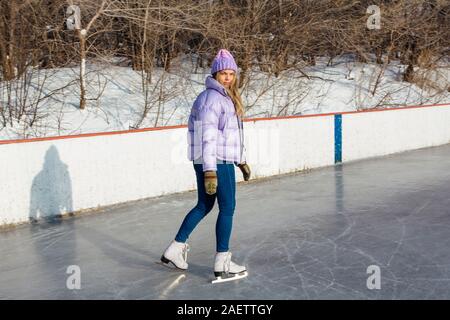 Reizende junge Frau, Schlittschuhe auf der Eisbahn. Stockfoto