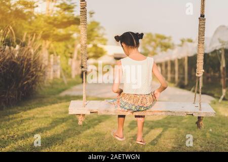 Zurück Blick auf junge Mädchen auf Schaukel sitzen für Ihre Mutter in der biologisch angebauten Trauben Bauernhof warten. Stockfoto