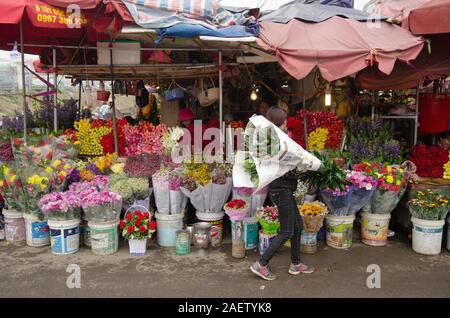 Ein Anbieter verkauft Blumen an ihrem Stall in einem Blumenmarkt in Hanoi, Vietnam Stockfoto