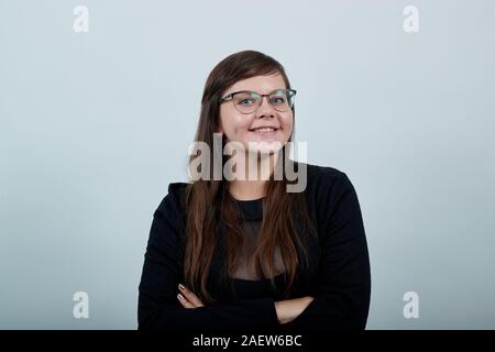 Lächelnde junge Frau in legere Kleidung, Hände gekreuzt, glücklich Stockfoto