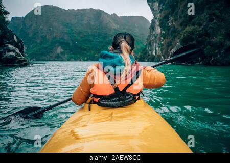 Mädchen Kajakfahren auf dem Meer der Halong Bucht in Vietnam. Frau Rudern Rudern im Boot. Der Blick von der Rückseite. Stockfoto