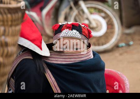 TA PHIN, Lao Cai, VIETNAM - 12. Januar 2019: Ein kleines Kind in einem Beutel hinter ein junges Mädchen. Roten Dzao - eine kleine Nation von North Vietnam Stockfoto