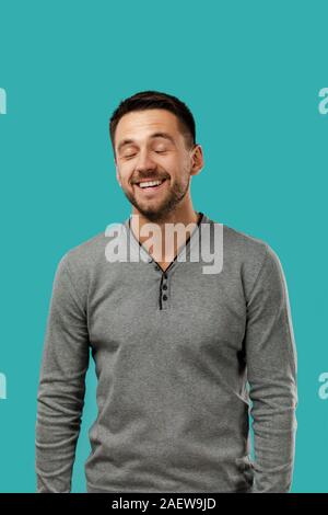 Close-up Portrait von glücklich aussehenden bärtigen Mann in grauen pullover auf blauem Hintergrund lachen Stockfoto