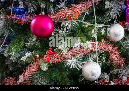 Nahaufnahme des Grünen Weihnachtsbaum und rosa Ball Dekorationen. Bunte Kugeln und Girlanden auf einer Tanne. Stockfoto