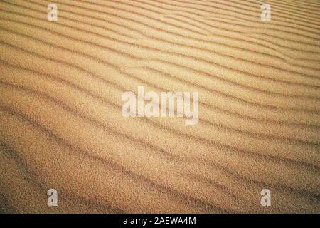Welle der Sand Textur. Mui Ne, Vietnam. Gelbe Sanddüne in der Sonne. Scheint die Sonne auf den Sand. Stockfoto