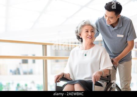Pflege Assistent kümmert sich um ältere Frau im Rollstuhl Stockfoto