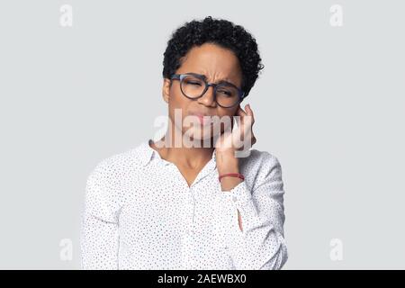 Gereizte afrikanische amerikanische junge Frau mit starken Ohrenschmerzen. Stockfoto