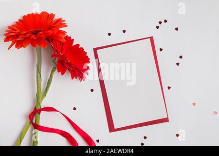 Eine leere Karte und rote Gerbera Blumen auf weißem Hintergrund Stockfoto