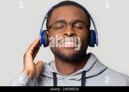 Tausendjährigen afrikanischen amerikanischen Mann, der modernen drahtlosen Ohrhörer zufrieden. Stockfoto