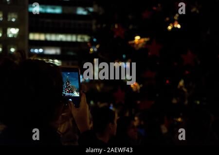 Athen, Griechenland. 10 Jan, 2020. Eine Frau ein Bild von den Weihnachtsbaum mit Ihrem Smartphone während der Veranstaltung. Die Beleuchtung der Athen Weihnachtsbaum ist ein jährliches Fest, das jedes Jahr stattfindet in der zentralen Syntagma-Platz in der Nähe des griechischen Parlaments. Es ist eine Feier über Weihnachten mit live Musik und anderen Happenings. Credit: Nikos Pekiaridis/SOPA Images/ZUMA Draht/Alamy leben Nachrichten Stockfoto