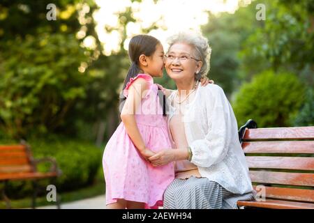 Gerne Großmutter und Enkelin Flüstern in Park Stockfoto