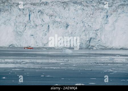 Red Passagier Schiff segeln durch den eisigen Gewässern der Qasigiannguit, Grönland mit Eqip Sermia Eqi Gletscher im Hintergrund. Ein kleines Boot unter Stockfoto