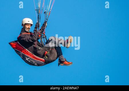 Bärtiger Mann in einem Paragliding rig im Flug sitzen, Vollbild und blauer Himmel, kopieren Raum Stockfoto