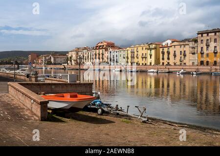 Bunte alte Häuser am Ufer des Fluss Temo, mit vielen Booten. Red Boat an der Promenade. Regnerische bewölkten Himmel. Bosa, Sardinien, Italien. Stockfoto