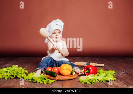 der junge Koch mit einem Holzlöffel, Karotten, Paprika, Tomaten, Salat, Gurke Stockfoto