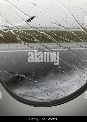 Regentropfen auf dem Flugzeugfenster beim Start auf einer Landebahn am Flughafen Barcelona Stockfoto