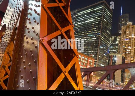 Nacht detail Aufnahme der Brücke überführung Stahlstützen mit städtischen Skyline der Stadt beleuchtet im Hintergrund Stockfoto