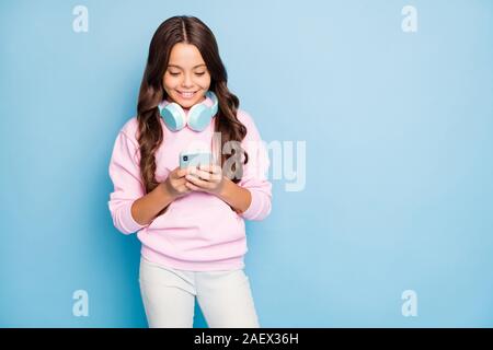 Foto des hübschen kleinen Frau telefon Hände Einschalten neu beliebte Jugend Song in drahtlosen Ohrenschützern lässiger Hoodie pink Pullover tragen isoliert Stockfoto