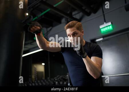 Junge boxer Mann Züge mit Boxsack in der Turnhalle Stockfoto