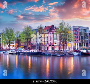 Bunte Frühjahr Sonnenuntergang auf den Grachten von Amsterdam. Authentische niederländische Architektur in der Hauptstadt und die bevölkerungsreichste Stadt der Niederlande. Stockfoto