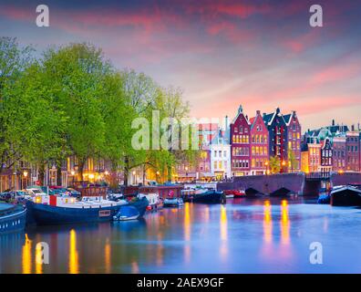 Bunte Frühjahr Sonnenuntergang auf den Grachten von Amsterdam. Authentische niederländische Architektur in der Hauptstadt und die bevölkerungsreichste Stadt der Niederlande. Stockfoto