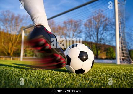 Fußball oder Soccer Shot mit einem neutralen Design Ball gekickt, mit Motion Blur auf dem Fuß und natürlichen Hintergrund Stockfoto