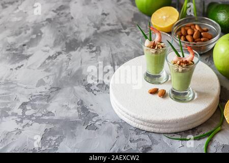 Avocado- und grüner Apfel Mousse mit Garnelen und Mandeln. Teil Vorspeise für ein Buffet oder Bankett in ein Glas. Stockfoto