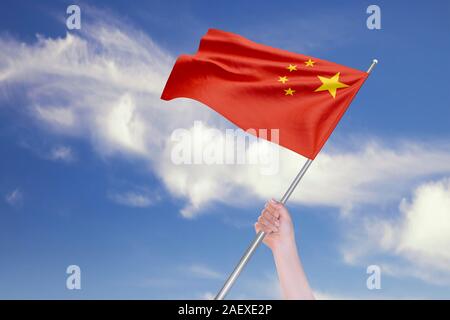 Weibliche hand winkt der Chinesischen Flagge gegen den blauen Himmel mit Wolken. Realistische Spiegelungen und Texturen mit hoher Auflösung. 3D-Rendering. Stockfoto