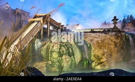 Weitwinkelansicht des fließenden schwefelhaltigen Wassers am Heißwasserfeld (Yubatake) im Kusatsu Onsen Thermalbad in Gunma, Japan, an einem bewölkten Tag. Stockfoto