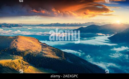 Farbenfrohe Sommer Sonnenaufgang in den Dolomiten. Morgen Blick von furchetta Peak auf Santa Magdalena Dorf unter einem Meer von Nebel. Provinz Bozen Süd T Stockfoto