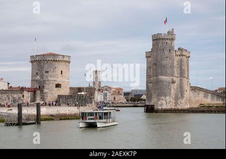 Turm Saint-Nicolas, die Kette Tower und ein Wassertaxi, das Verlassen des alten Hafens (Vieux Port) mit Kirche Saint-Sauveur im Hintergrund, La Rochelle, C Stockfoto
