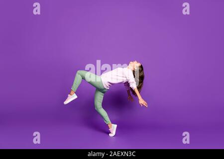 Volle Länge Körper Größe Foto von fröhlichen Niedlich süß hübsche Freundin Seite Profil balancing Lachen tanzen über violett leuchtenden Farben isoliert Stockfoto
