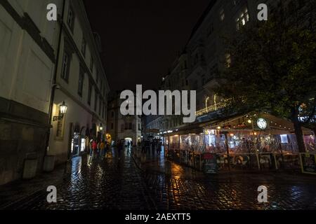 Prag, Tschechien - NOVEMBER 3, 2019: Karlova Straße bei Nacht mit Touristen vorbei. Die Straße, gepflastert mit Kopfsteinpflaster, ist ein Wahrzeichen der Stockfoto