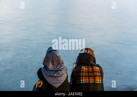 Zwei weibliche muslimische Touristen den Sonnenuntergang an der Corniche Park am Uskudar Istanbul, Istanbul, Türkei, auf die Anatolische Ufer des Bosporus. Stockfoto