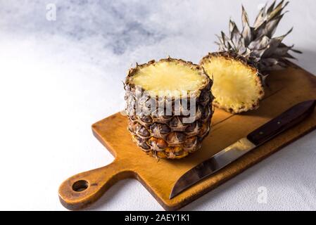 Ananas auf Holz Textur Hintergrund. Ganze und aufgeschnittene ​​Tropical Ananas auf ein Holzbrett. Ansicht von oben mit Platz für Ihren Text. Stockfoto