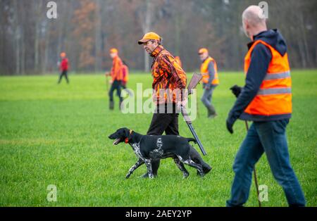 REUTUM, Niederlande - 07 Dez, 2019: Männer mit Schrotflinte und Sticks sind zu Fuß auf einer Linie in einem offenen Feld Jagd auf Hasen en Fasane. Stockfoto