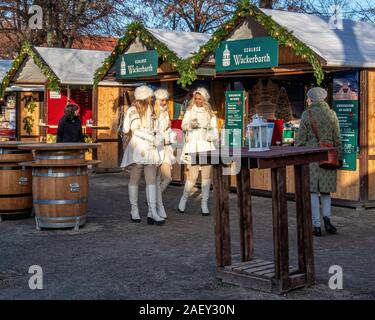 Drei Frauen in cremefarbenen Kleidung an der traditionellen Deutschen Weihnachtsmarkt geht im Schloss Charlottenburg in Berlin. Stockfoto