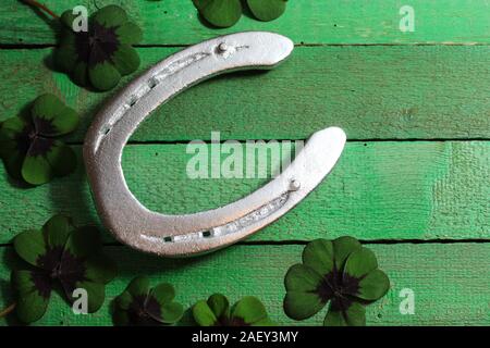 Das Bild zeigt ein Hufeisen und Glücksklee auf grüne Karten Stockfoto