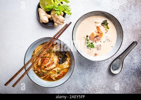 Satz serviert asiatische Suppen auf grauem Hintergrund der Ansicht von oben. Tom Yum Suppe, Aal Fischsuppe und Ramen Noodle Soup Stockfoto