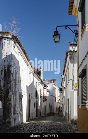 Der Blick auf die gepflasterte Straße von Evora mit der gemütlichen weißen Häusern. Evora. Alentejo. Portugal Stockfoto