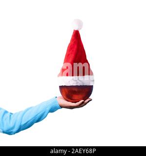 Weihnachten roten Ball in santa claus Hut auf der Hand, auf weißem Hintergrund, frohe Weihnachten Konzept Stockfoto